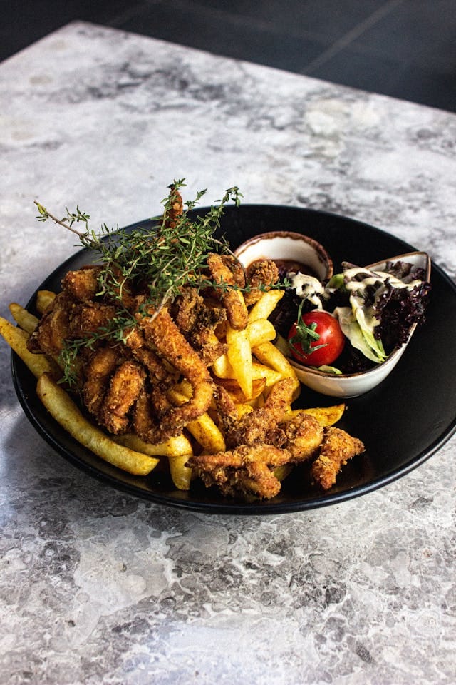 Fried Chicken and French Fries on Black Plate | Photo by Ayberk Mirza
